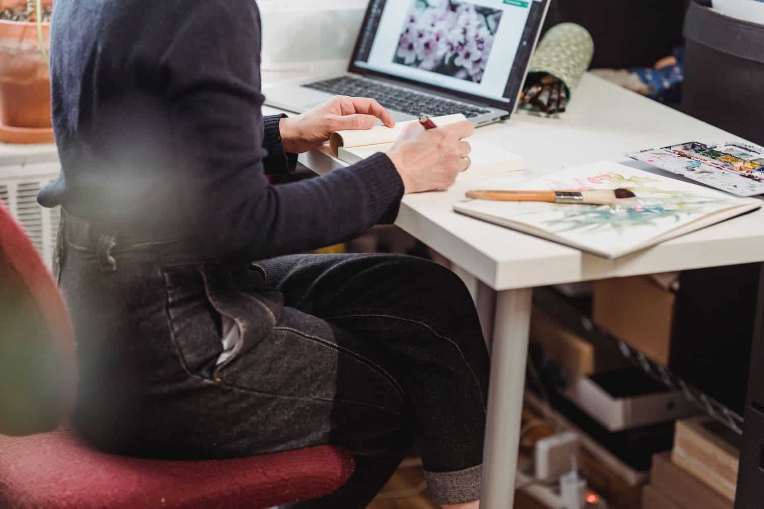Artist using a tablet and stylus to create digital artwork at a desk.